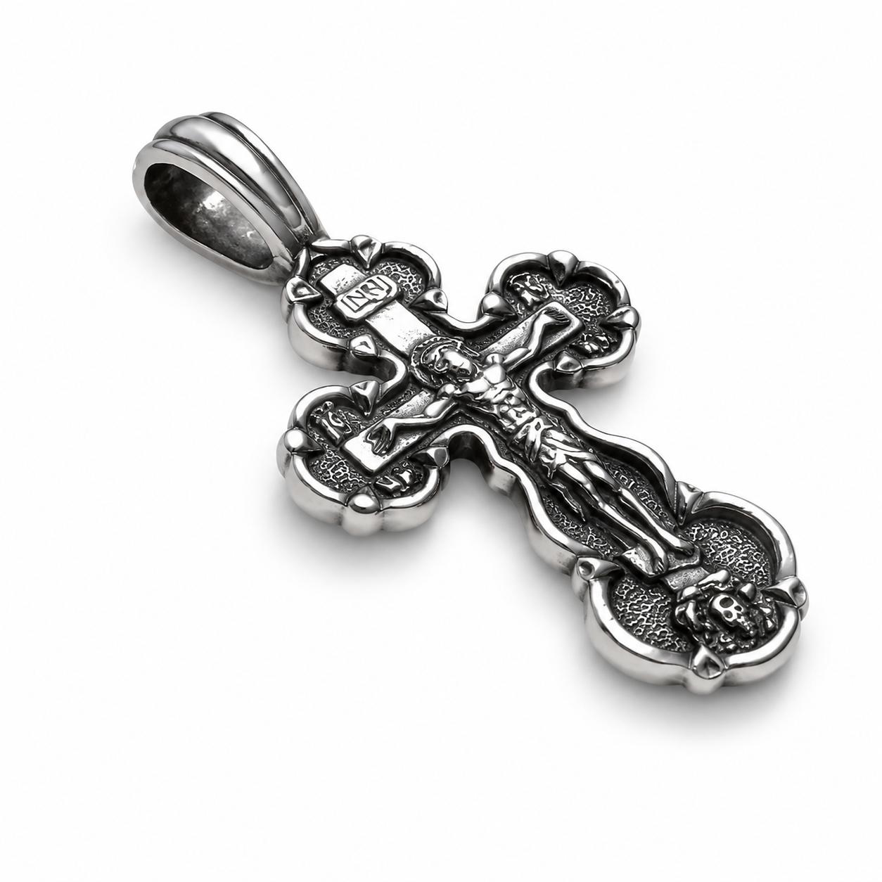 Angled view of an oxidized 925 sterling silver Orthodox crucifix pendant with Jesus figure, INRI plaque, rounded cross ends, polished bail, raised details, and dark textured recesses on a white background.
