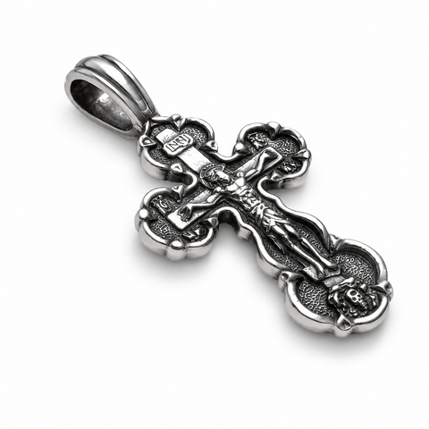 Angled view of an oxidized 925 sterling silver Orthodox crucifix pendant with Jesus figure, INRI plaque, rounded cross ends, polished bail, raised details, and dark textured recesses on a white background.