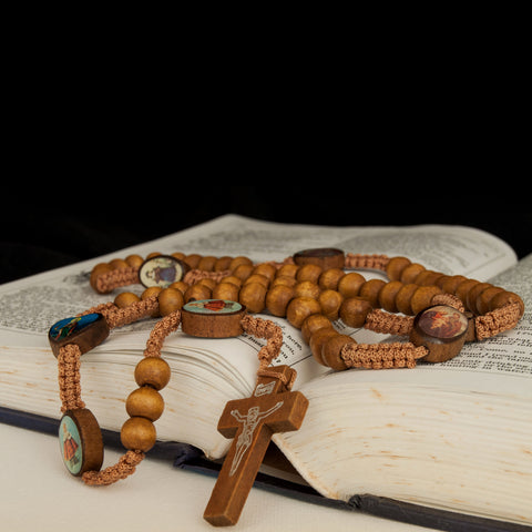 Engraved saints detail on natural wood rosary cross centerpiece
