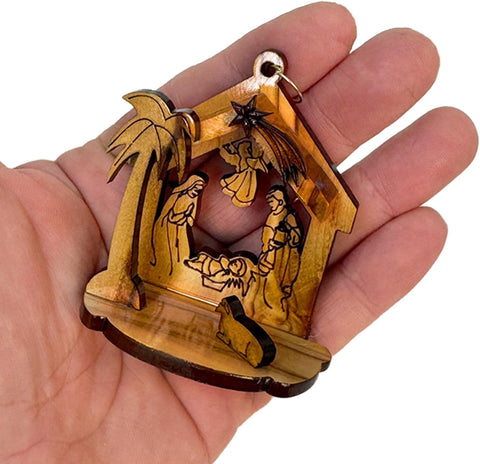 Wooden nativity scene ornament held in a hand against a white background
