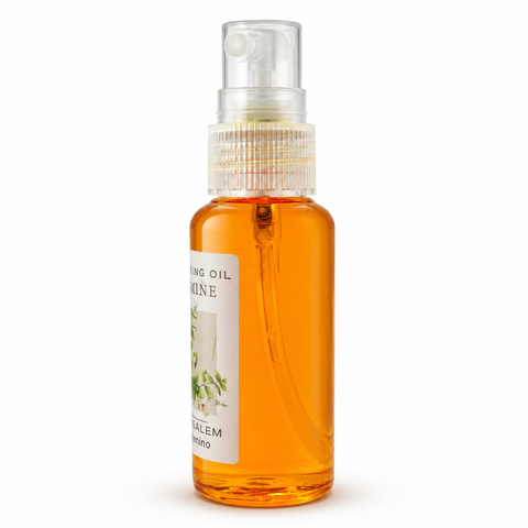 Side view of clear spray bottle filled with amber Jasmine anointing oil, partial white floral label, visible inner spray tube, transparent cap, on white background
