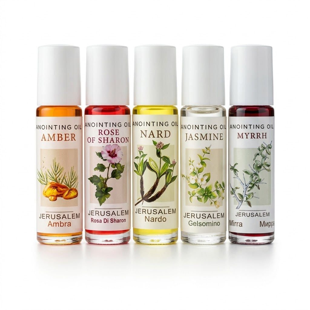 Five clear glass roll-on bottles labeled Jerusalem Anointing Oil in Amber, Rose of Sharon, Nard, Jasmine, and Myrrh. Colored liquids with botanical illustrations on cream labels and white caps, lined up on a solid white background.