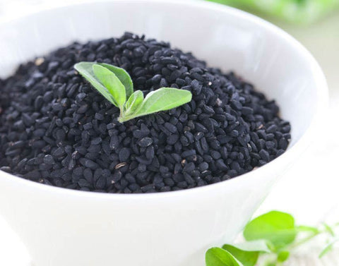 Black caraway seeds and ground spice blend on a table
