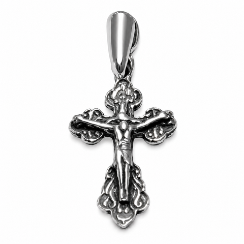 Silver crucifix pendant with raised Jesus figure, ornate scroll details, polished bail, dark recessed accents, front view on a plain white background